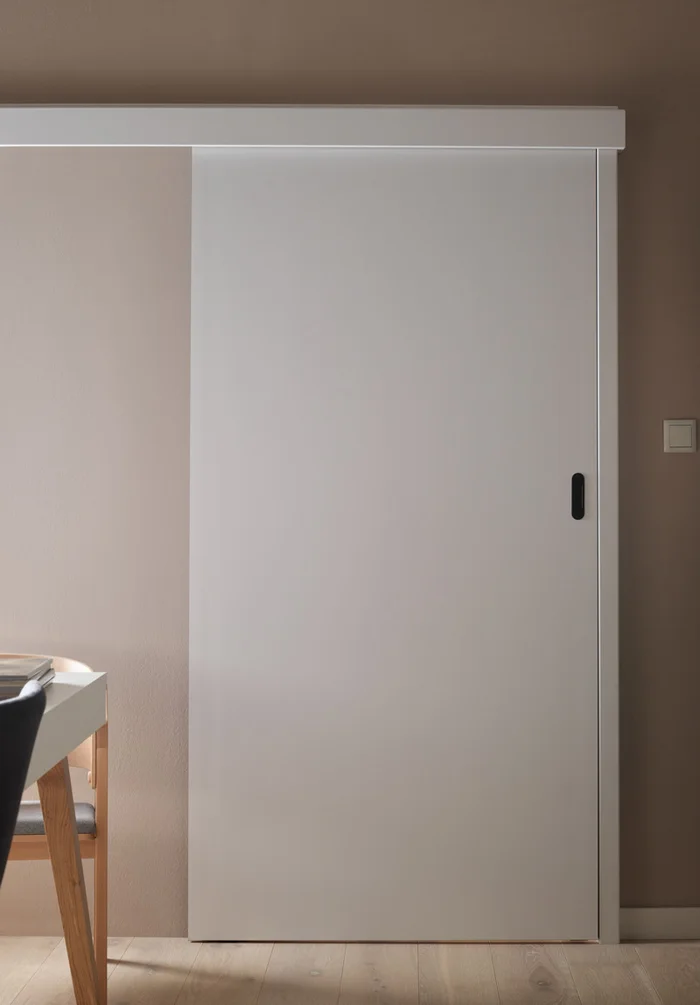 Proste białe drzwi przesuwne w minimalistycznym wnętrzu.
